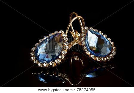 Earrings From Gold Against A Dark Background.