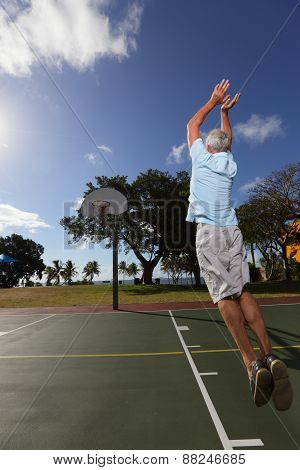 Handsome active senior playing basketball
