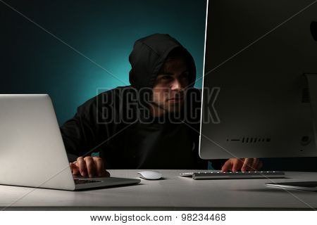 Hacker with computer and laptop on dark background 
