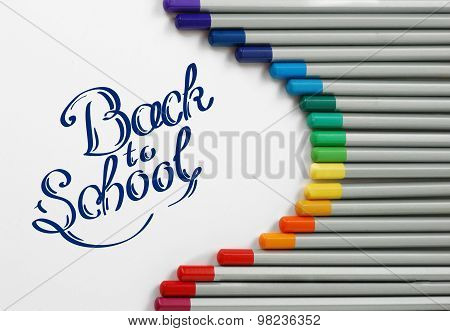 Sharpened monochrome watercolor pencils with multicolor slate-pencil on a white background and hand