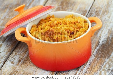 Polish bigos in saucepan with open lid on rustic wooden surface