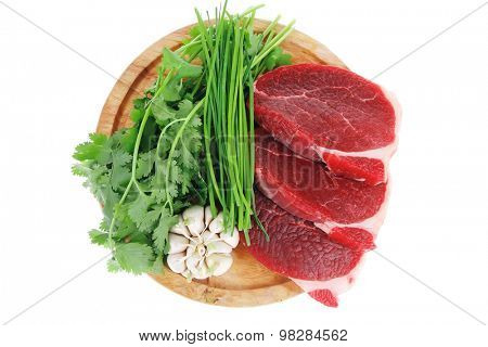 butchery : fresh raw beef lamb fillet ready to cooking with green stuff on wooden plate isolated over white background