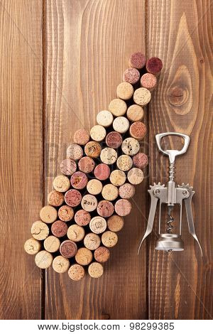 Wine bottle shaped corks and corkscrew over rustic wooden table background. Top view