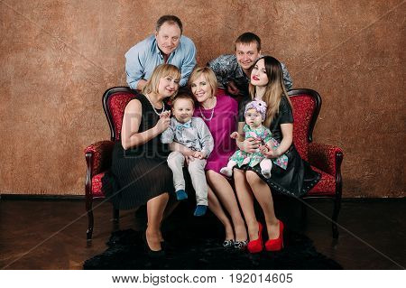 Three Generation Family Sitting On Sofa Together. Classic Portrait