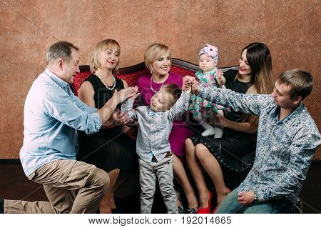 Three Generation Family Sitting On Sofa Together. Classic Portrait