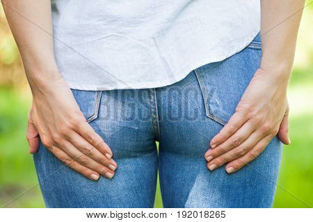 Close up picture of a young woman holding her butt she needs to poop outdoor