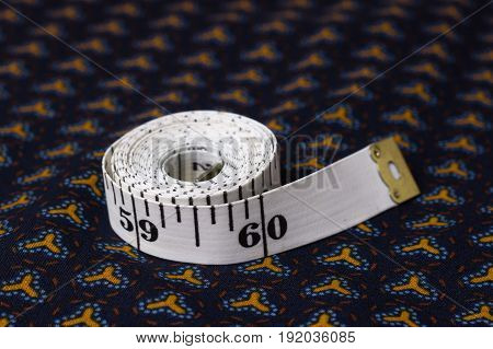 Inch, Centimeter Tape On A Background Of Blue Fabric With A Pattern