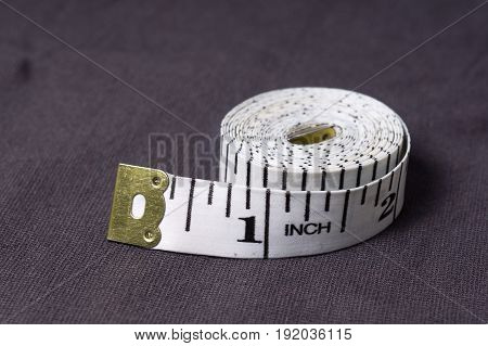 Inch, Centimeter Tape On A Background Of Grey Fabric