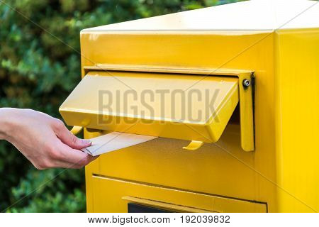 Throwing A Letter In A Yellow Mailbox