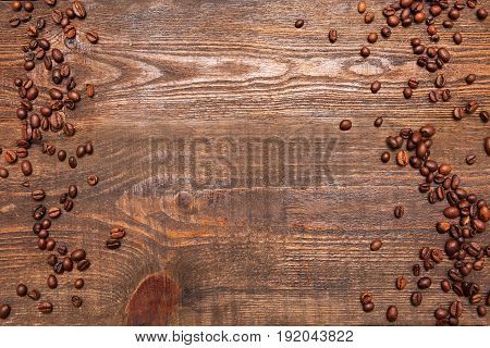 Roasted coffee beans frame on wooden background. Closeup of seeds on dark brown table. Top view.