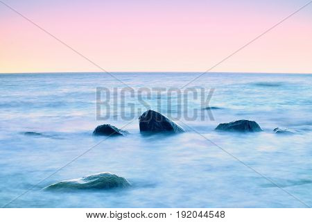 Romantic Morning At Sea. Big Boulders Sticking Out From Smooth Water Level. Pink Horozon With First