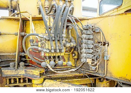 Hydraulic pressure pipes and connection fittings levers valves on control panel of industrial system on construction machinery.
