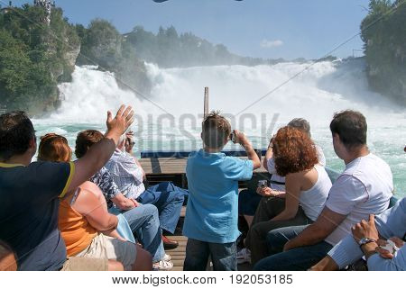 People In A Tourist Boat Approaching The Rhine Waterfalls