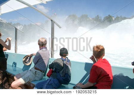 People In A Tourist Boat Approaching The Rhine Waterfalls