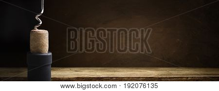 Bottle of wine with corkscrew on wooden background.