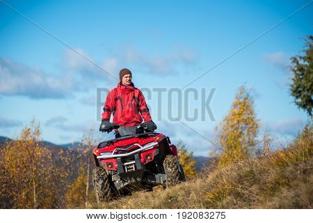 Bottom View. A Guy On The Red Atv Quad Bike Against Blue Sky In The Autumn Landscape Nature. Sunny D