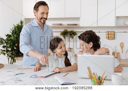 Interesting explanation. Handsome wavy-haired son paying great attention to his father inscribing a circle with a pair of compasses while his sister looking at him with a smile