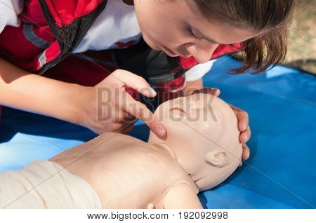 Infant Resuscitation On Cpr Dummy By Young Woman, Color Image