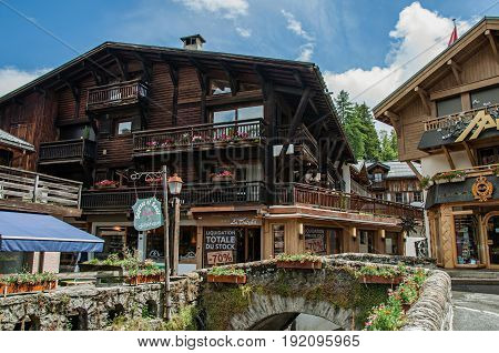 Megève, France - June 25, 2016. View of street with shop buildings, creek and cloudy sky. Megève is a famous ski resort located in Haute-Savoie Province, near the Mont Blanc in the French Alps