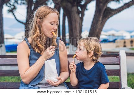 Mom And Son Eat Fried Sweet Potatoes In The Park. Junk Food Concept