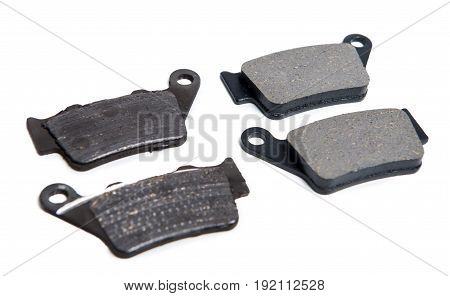 New and used brake pads for a motorcycle on white