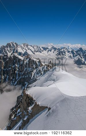 View of snowy peaks from the Aiguille du Midi, in French Alps Chamonix Mont Blanc, alpine mountains landscape, clear blue sky in warm sunny summer day.