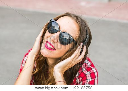 Young smiling woman relaxing and listening to music with headphones in the street
