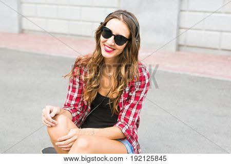 Young smiling woman relaxing and listening to music with headphones in the street