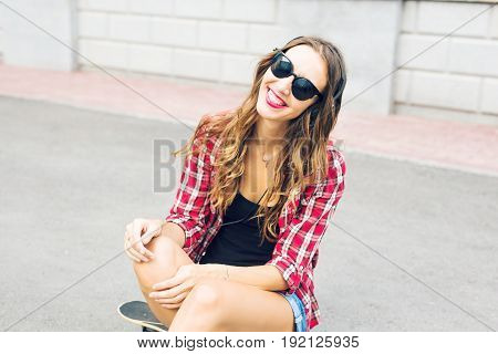Young smiling woman relaxing and listening to music with headphones in the street