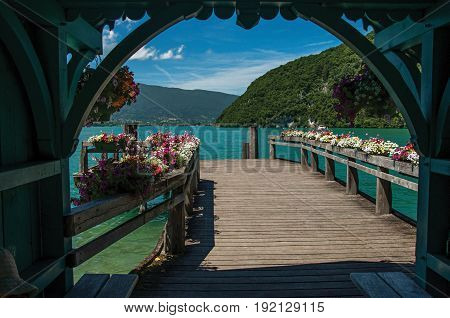 Pier with flowers on the lake of Annecy, in the village of Talloires. Mountains landscape and blue sky on background. France