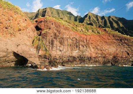 Sea arch and waterfall on Na Pali coastline in Kauai from sunset cruise