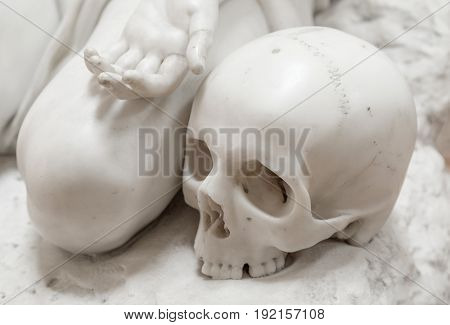 Stone statue of human skull with hand.