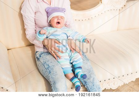 Newborn baby yawning. Wearing cute blue sweater.