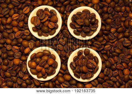 Four white saucers full of fragrant coffee beans close-up