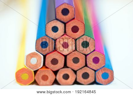 A pyramid of colored pencils at a white background close-up