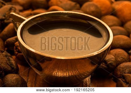 A cup with morning black coffee among coffee beans close-up