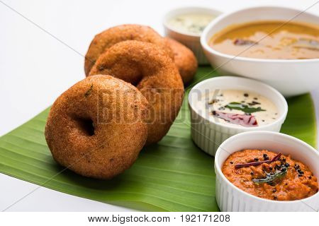 south indian food called vada sambar or sambar vada or wada, served with coconut, green and red chutney over fresg banana leaf, selective focus
