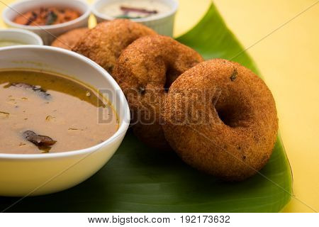 south indian food called vada sambar or sambar vada or wada, served with coconut, green and red chutney over fresg banana leaf, selective focus