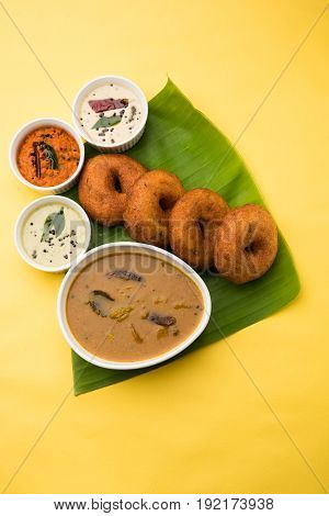 south indian food called vada sambar or sambar vada or wada, served with coconut, green and red chutney over fresg banana leaf, selective focus