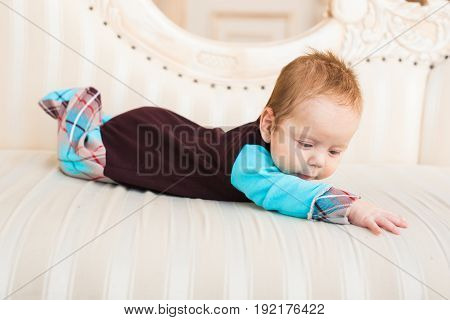 Adorable baby boy with red hair and blue eyes. Newborn child lyling in couch