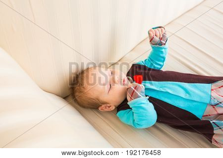 Adorable baby boy with red hair and blue eyes. Newborn child lyling in couch