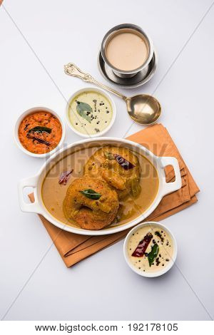 south indian food called vada sambar or sambar vada or wada dipped in sambar with coconut, green and red chutney and south indian style hot coffee, selective focus