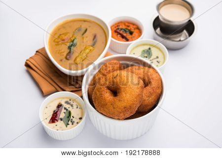 south indian food called vada sambar or sambar vada or wada, served with coconut, green and red chutney over fresg banana leaf, selective focus
