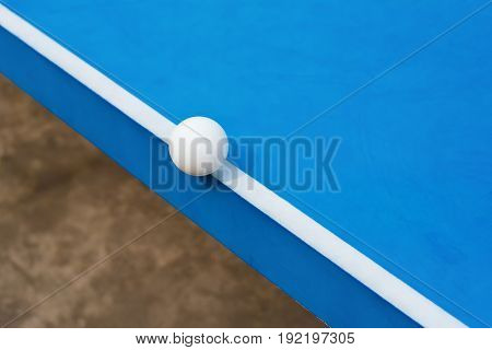 white pingpong ball hits the edge of a blue pingpong table