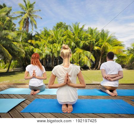 fitness, sport, yoga and healthy lifestyle concept - group of people exercising in reverse prayer pose over natural exotic background with palm trees