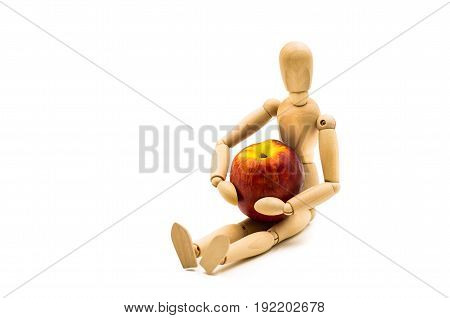 wooden man puppet sitting hugging a nectarine on white background