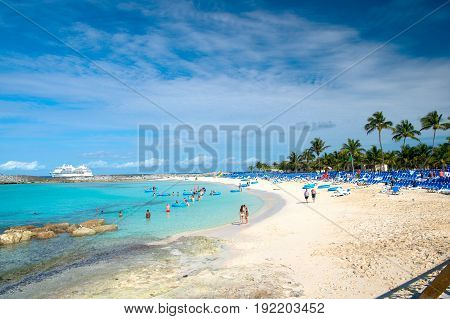 Great stirrup cay Bahamas - January 8 2016: people resting on beach on white sand with turquoise sea or ocean and lounge chairs on sunny day on blue sky. Summer vacation. Tropical resort. Paradise