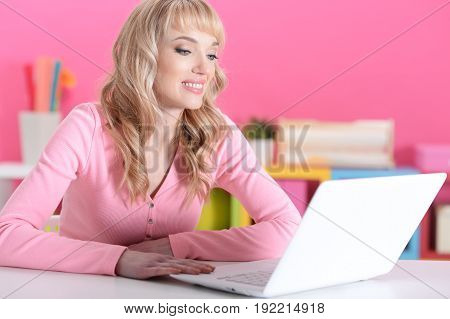 Portrait of beautiful young woman sitting at table with laptop