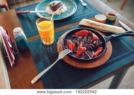 Mexican fajitos in a frying pan on a table.