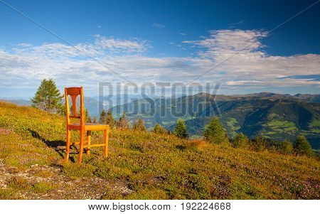 Old wooden chair on the top in Gerlitzen Apls in Austria.View of the mountains in Slovenia.